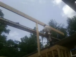 Carpenter setting a ridge beam over a new addition frame — Ice Dam Removal by Roofing Brothers in Colerain