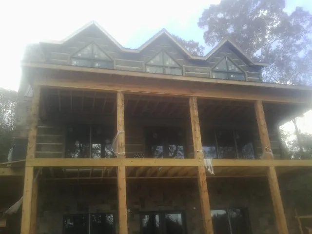 Dormers and porch framing on a large log home under construction — Roof Coating work by our crew in Colerain