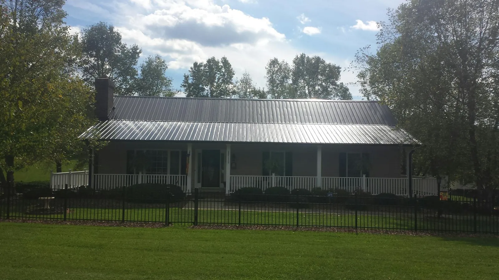 Gray metal roof on a brick ranch with a full width front porch — Gutter Guard Installation work by our crew in Colerain