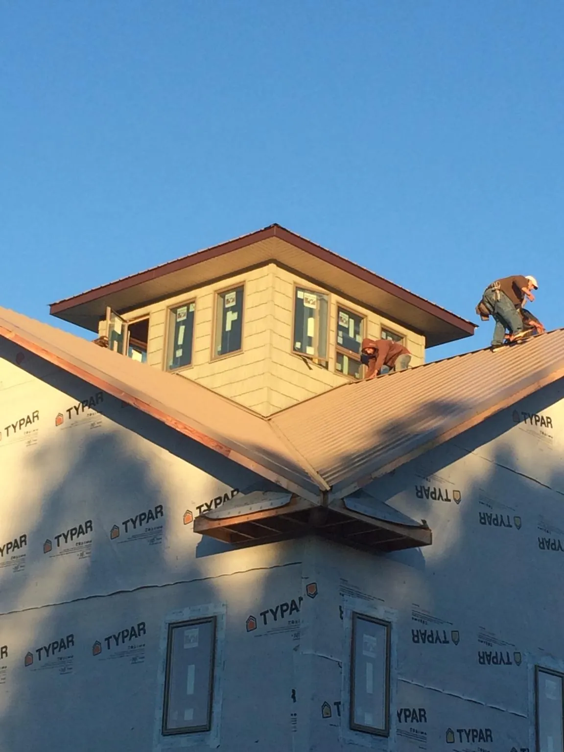 Roofers working around a rooftop cupola on a new metal roof at sunset — Roof Waterproofing in Colerain by Roofing Brothers